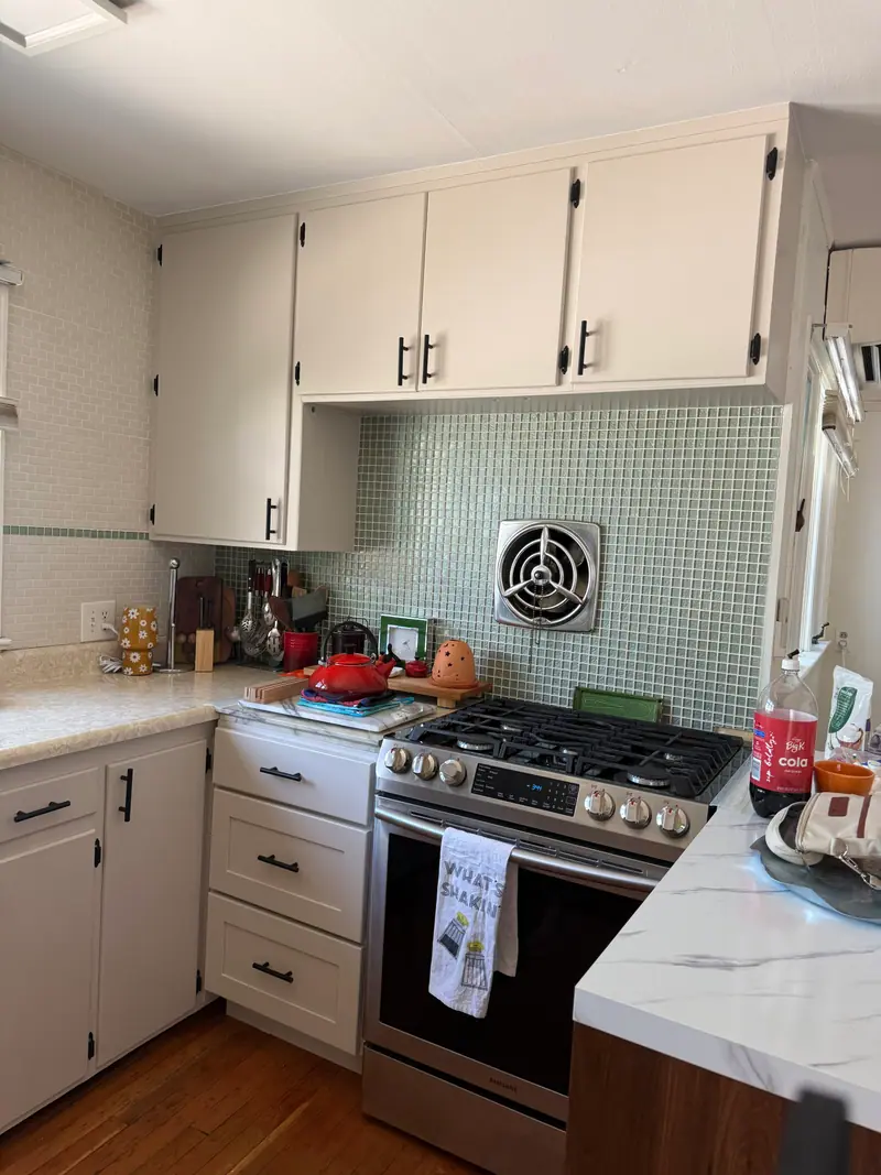 Kitchen after refinishing, with white cabinets and a tile backsplash